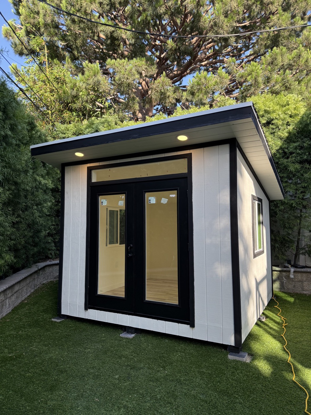 White 10 by 10 ft backyard office with black trim on a lawn in Redondo Beach