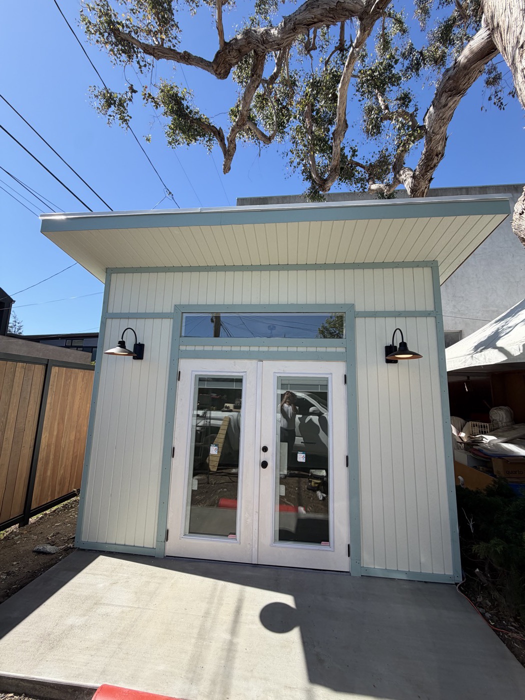 Front elevation of a sage green 12 by 12 ft yoga studio with barn lights