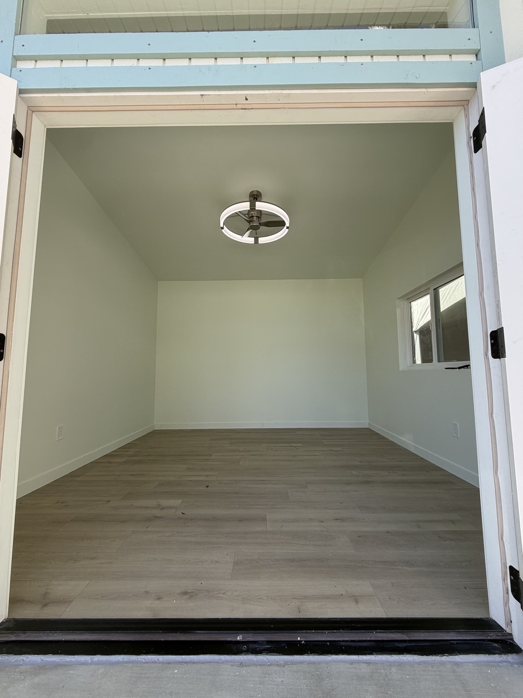 Interior of the 12 by 12 ft yoga studio with LVP flooring and a ceiling fan